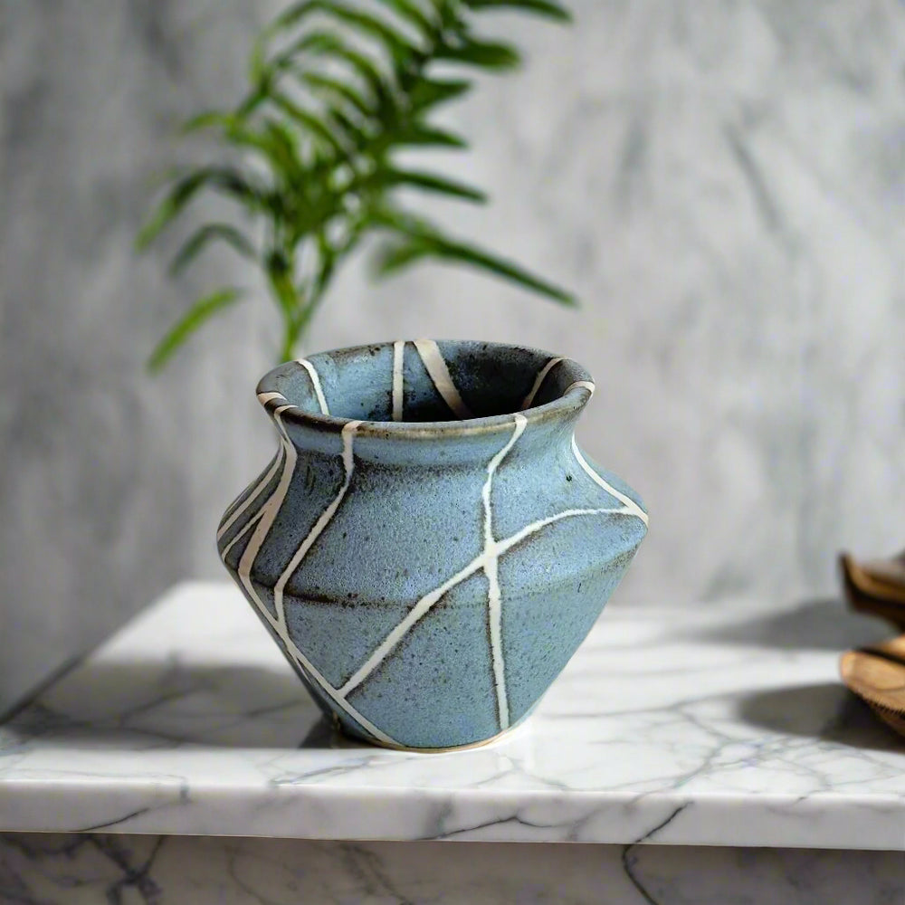 
                      
                        Medium sized vase with white lines in random patter against a matte light blue background. 
                      
                    