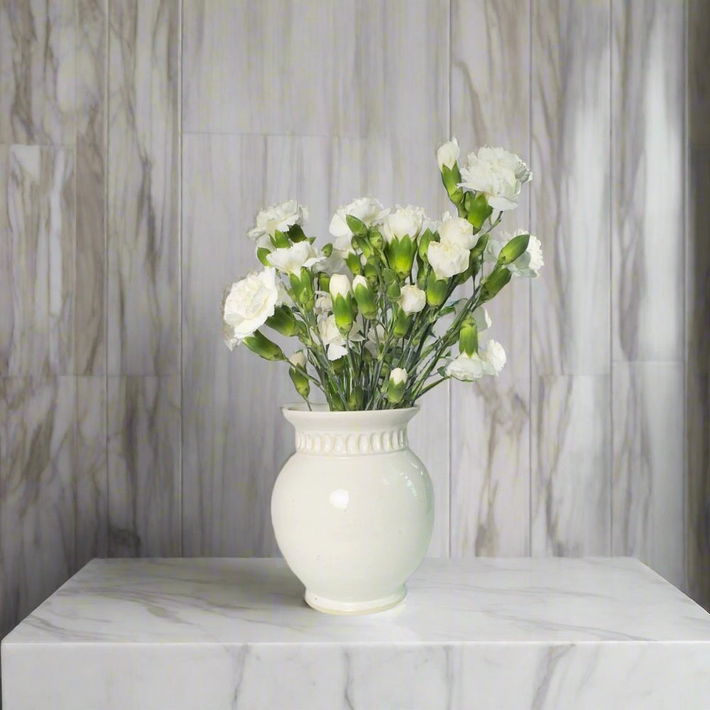 White vase with carvings and white flowers as decoration