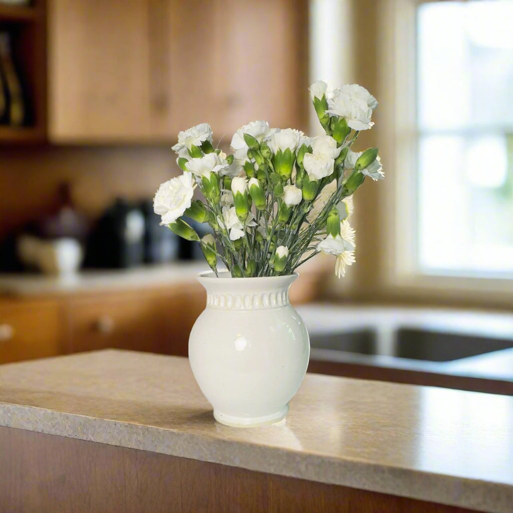 
                      
                        White vase with carvings and white flowers as decoration
                      
                    